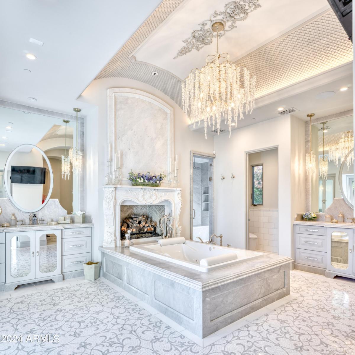 Bathroom with a soaking tub, chandelier, mirror and a fireplace.