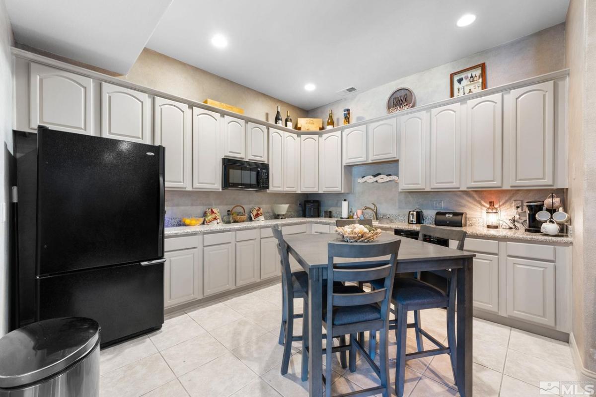 Kitchen with a black refrigerator, breakfast nook, custom lights and custom cabinets.