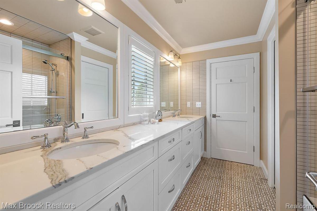 Bathroom with dual sinks, mirrors and a wooden door.