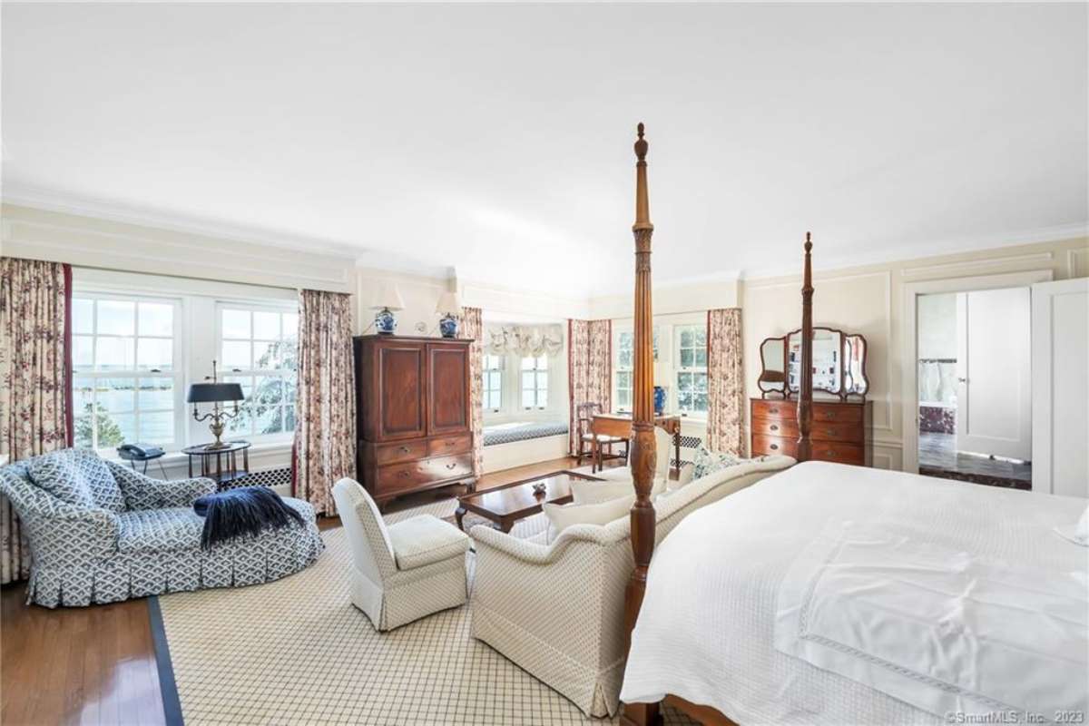 A bedroom with a bed, a rug, a white ceiling, windows, couches, and a coffee table.