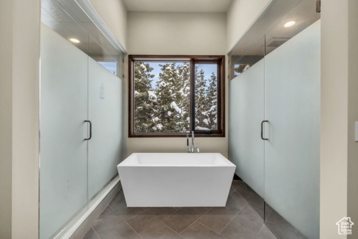 A bathroom with tiled floor, white ceiling, and white bathtub.