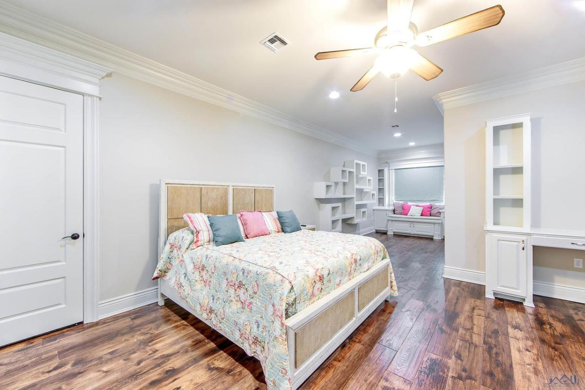 Bedroom with a large bed, wooden door and a wooden floor.