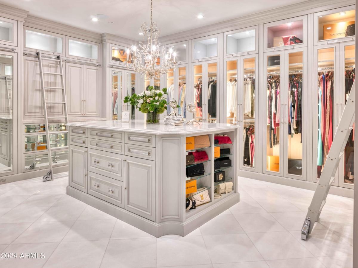 Walk-in closet with a chandelier, tile flooring and custom lights.
