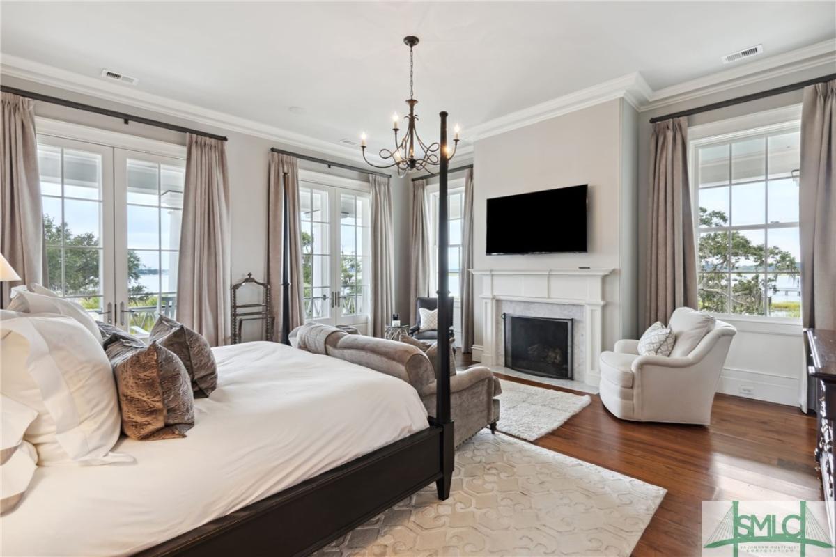 Bedroom with wood flooring, chandelier and a fireplace.