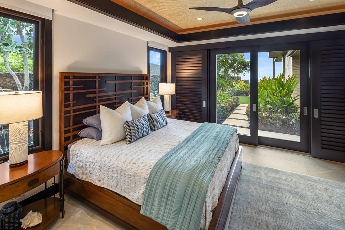 Bedroom with a large bed, glass doors and a carpet flooring.