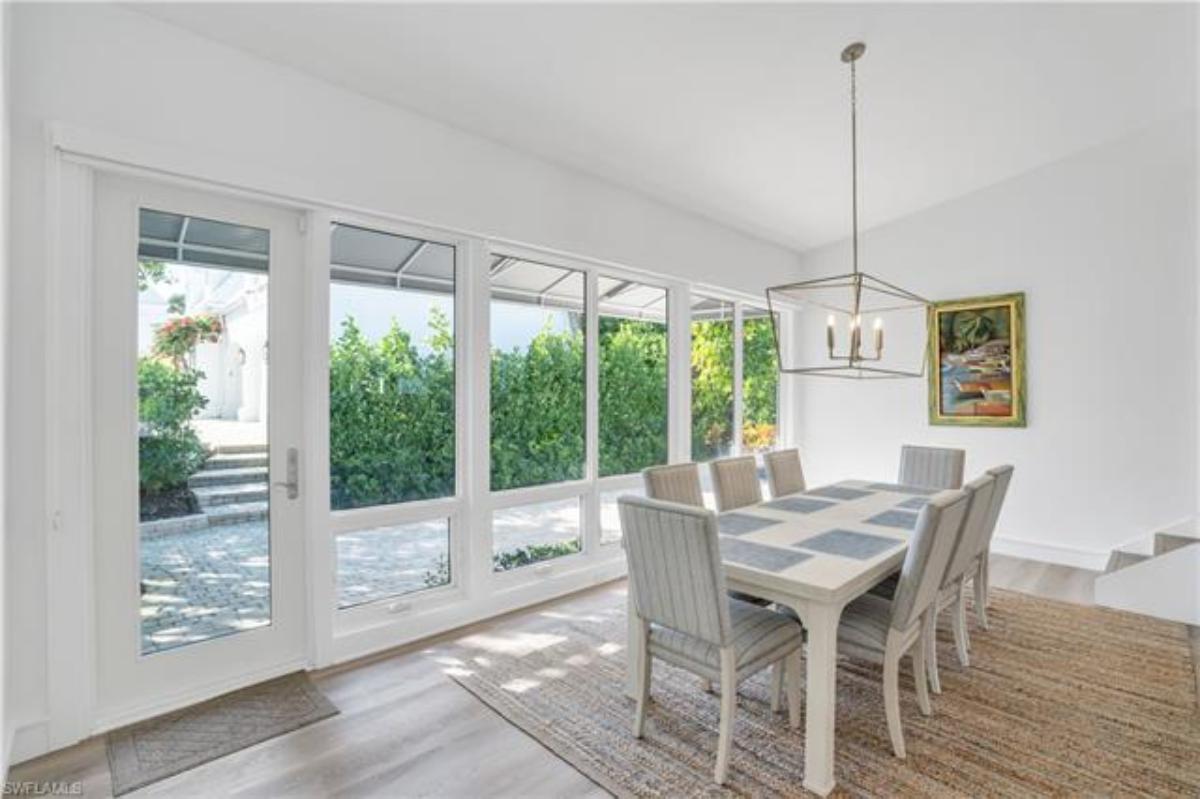 Dining room with a large table, chairs, glass walls and a glass door.