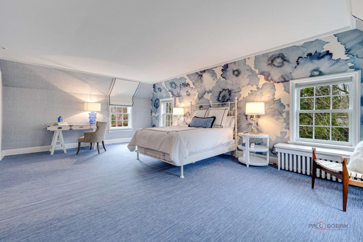 Bedroom with a large bed, carpet flooring and glass windows.