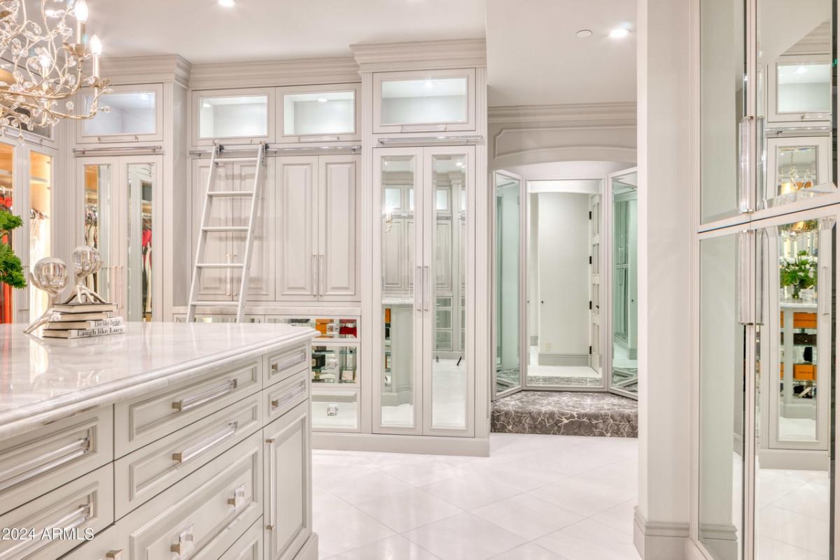 Walk-in closet with a chandelier, tile flooring and custom lights.