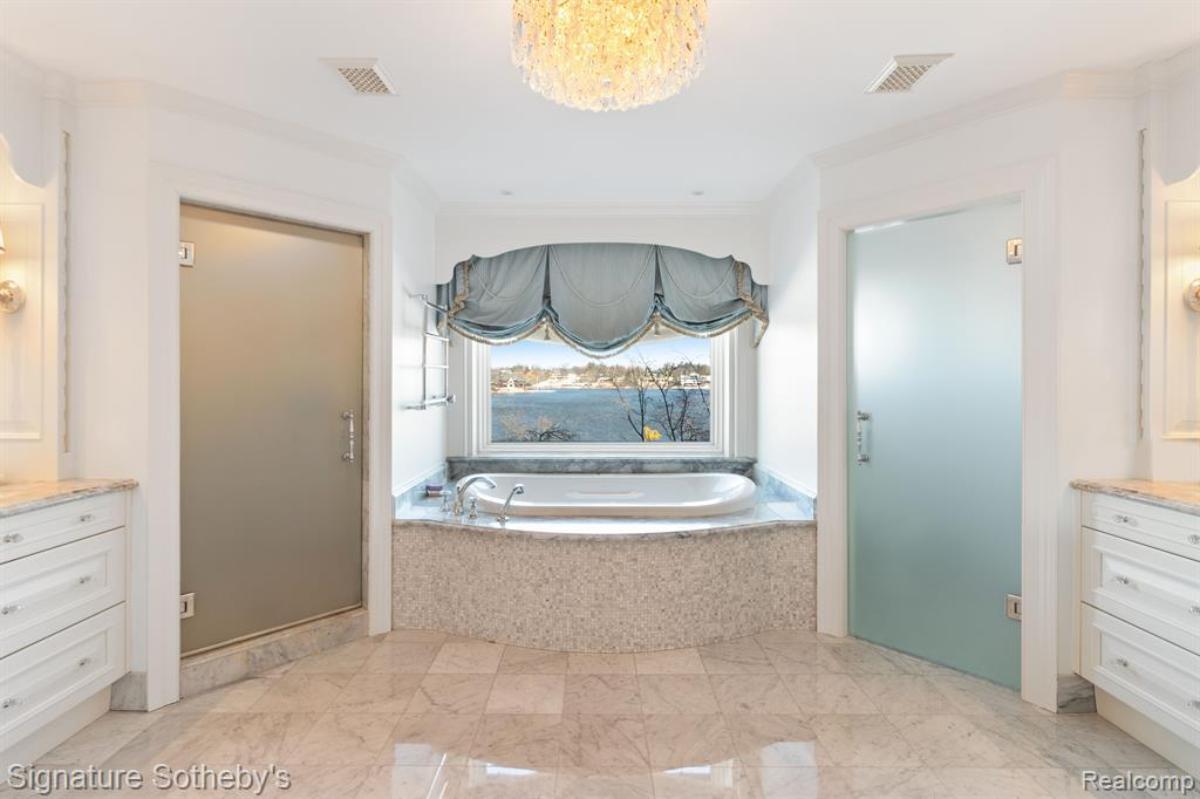 Bathroom with a soaking tub, glass windows and a chandelier.