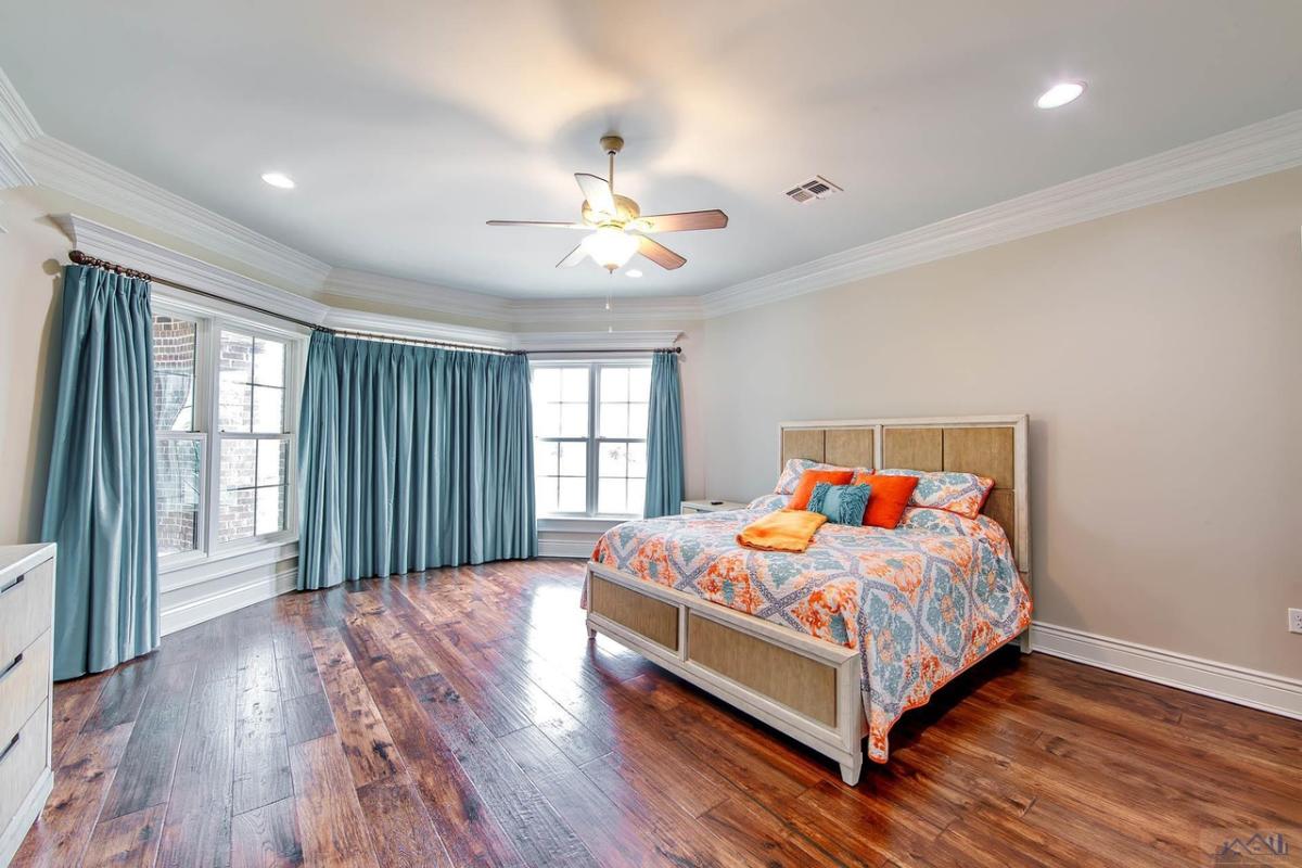 Bedroom with a large bed, large glass windows and a wooden floor.