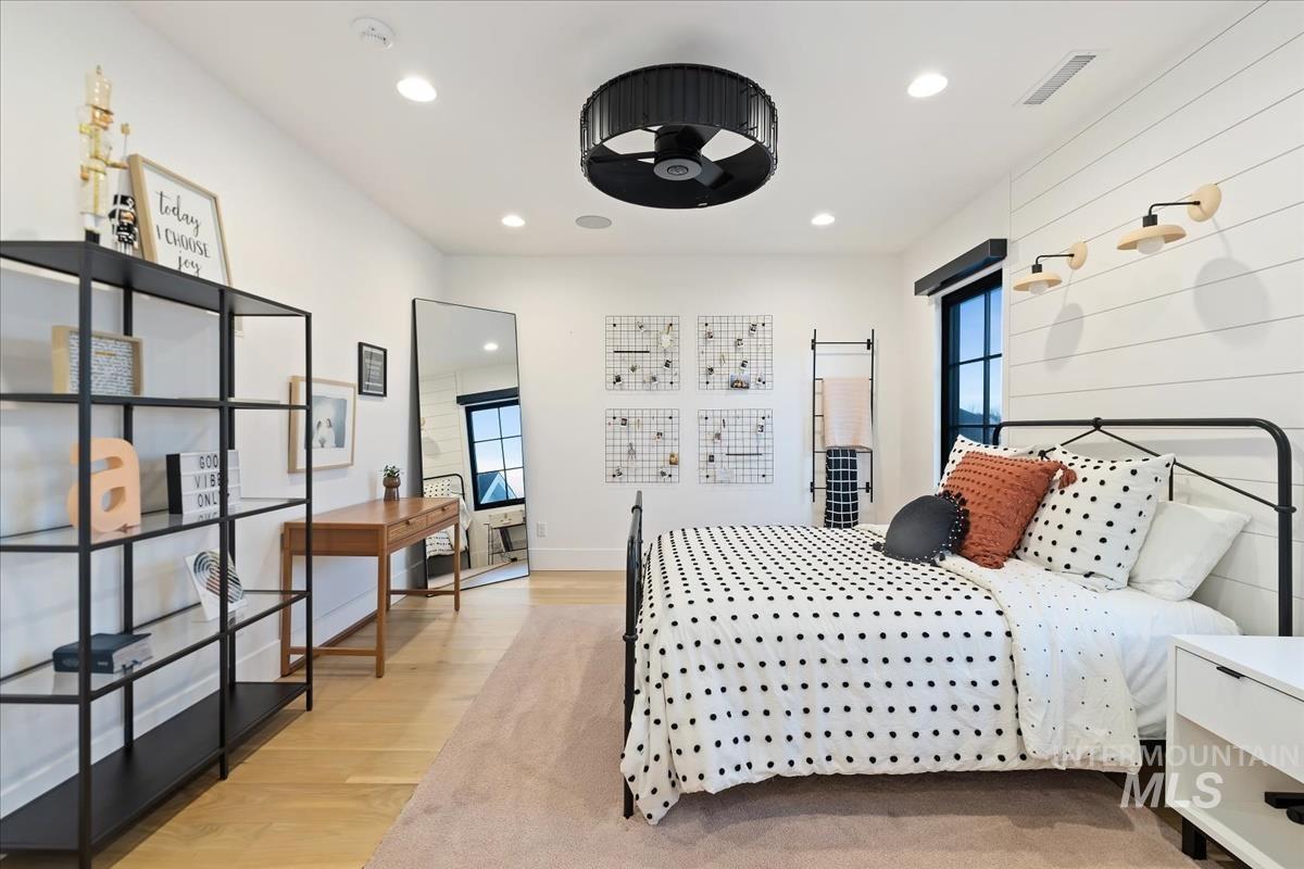 Bedroom with a large bed, wooden floor and custom lights.