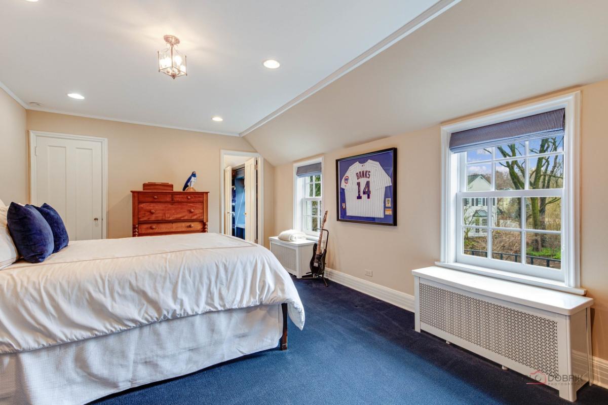Bedroom with a large bed, carpet flooring and glass windows.