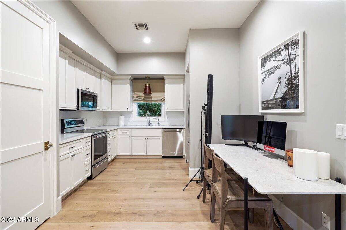 Kitchen with a wood flooring, stove and custom cabinets.