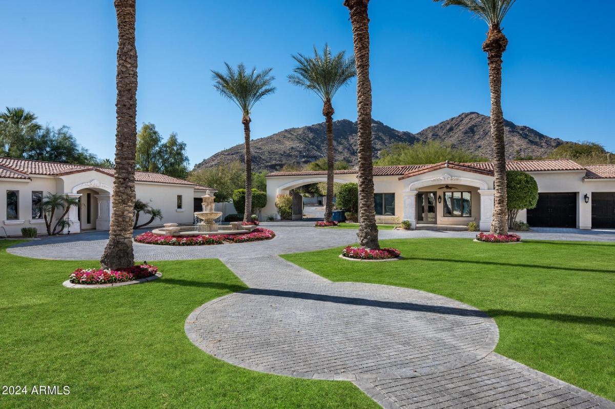 Front view of the mansion with fountain, driveway, walkway and a large lawn.