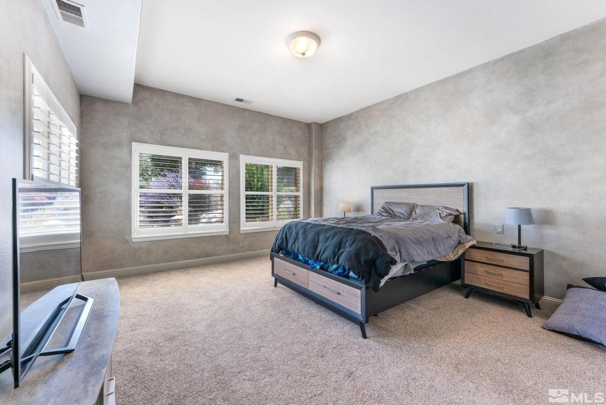Bedroom with a large bed, glass windows and carpet flooring.
