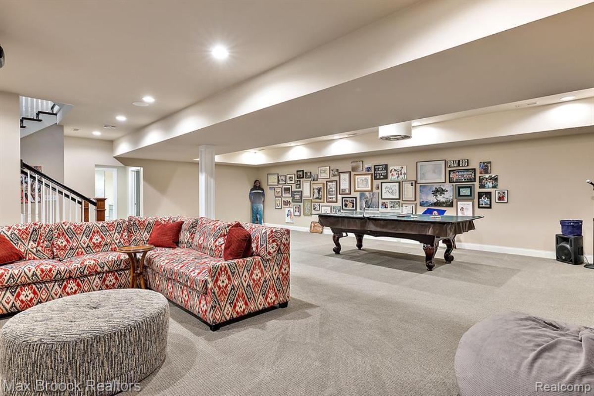 Entertainment room with a couch, pool table and carpet flooring.