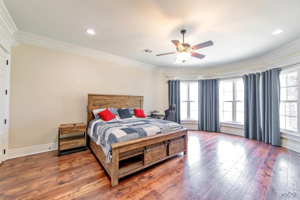 Bedroom with a large bed, large glass windows and a wooden floor.