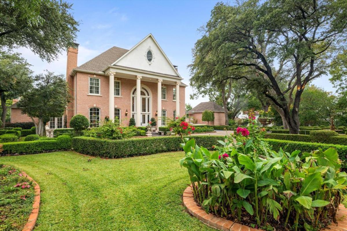 Front view of the mansion with manicured gardens.
