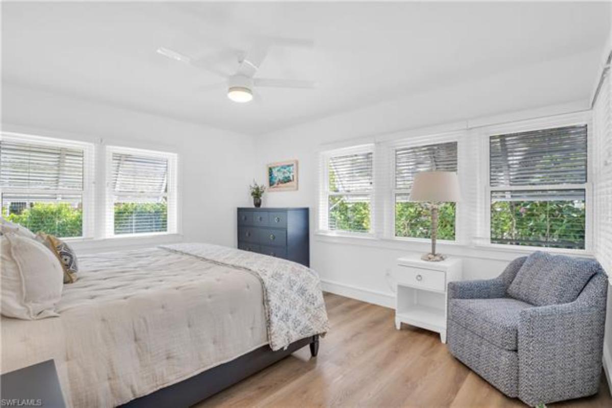 Bedroom with a large bed, glass windows and a wooden floor.