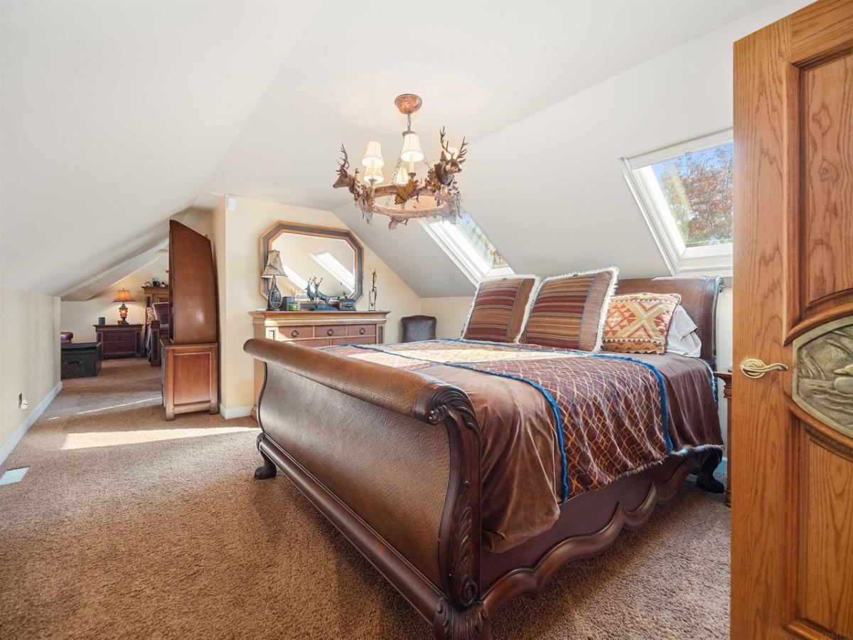 Bedroom with a large bed, chandelier and carpet flooring.