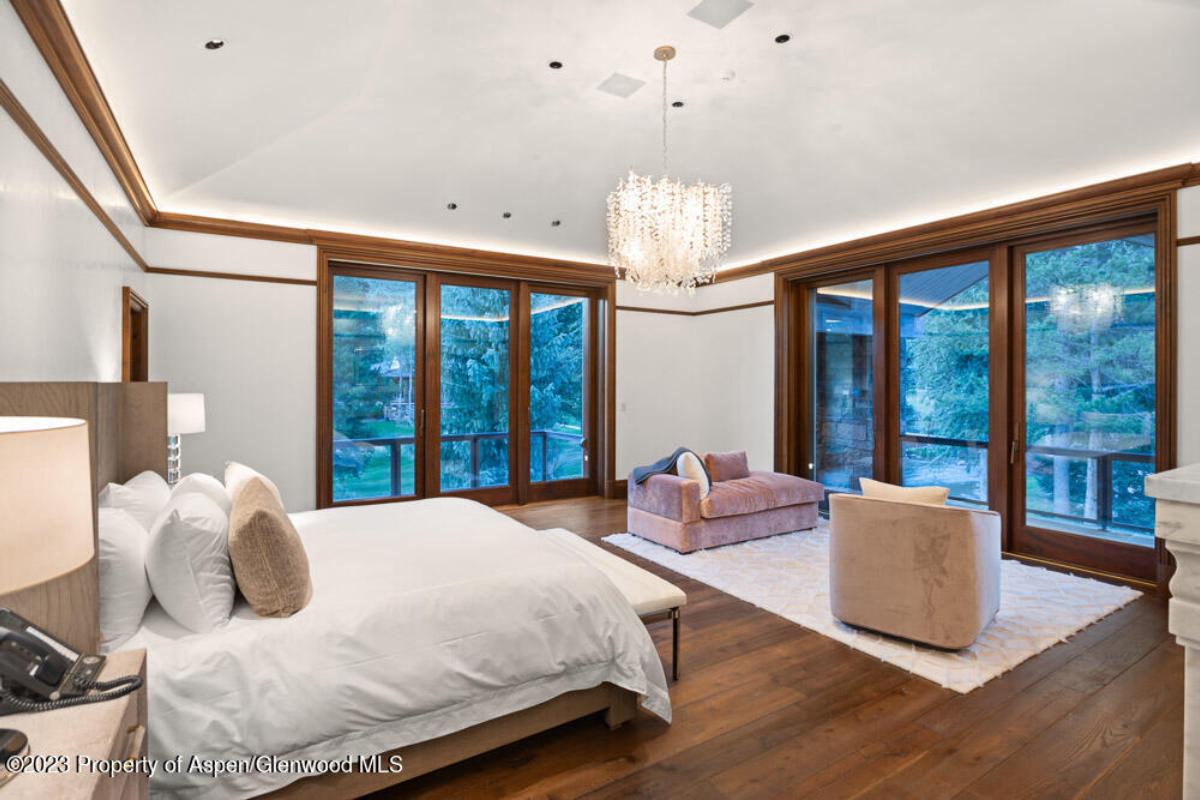 Bedroom with a large bed, chandelier, couch and a wooden floor.