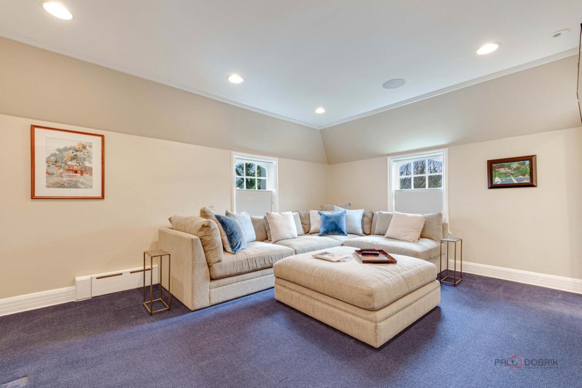 Sitting area with a couch, glass windows and carpet flooring.