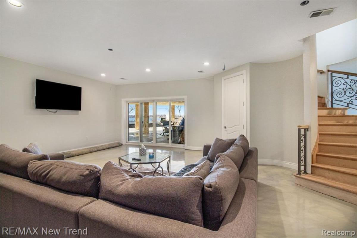 Living room with couches, TV, glass doors and a staircase.