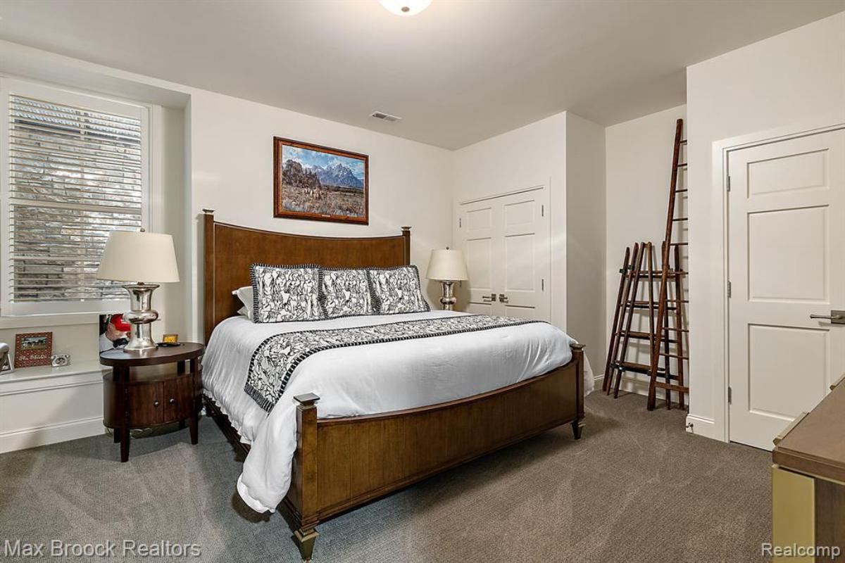 Bedroom with a large bed, glass windows and a carpet flooring.