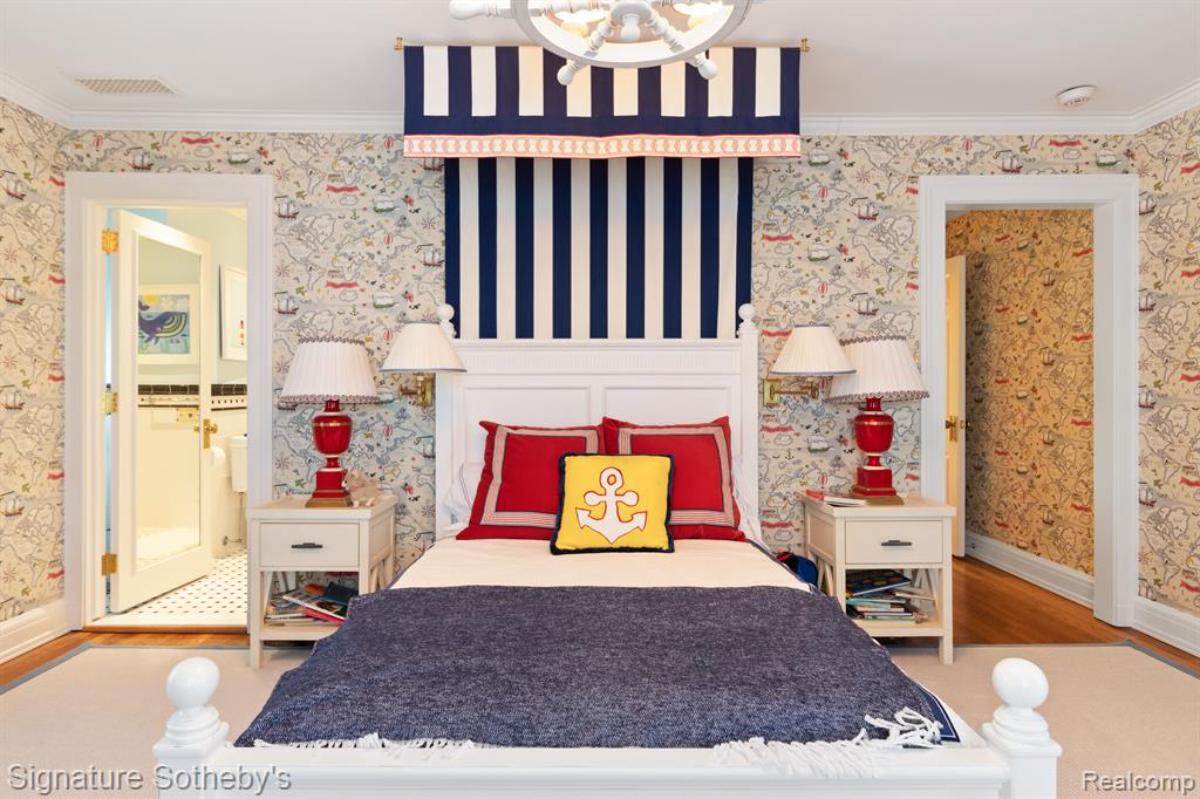 Bedroom with a large bed, chandelier and a large rug.