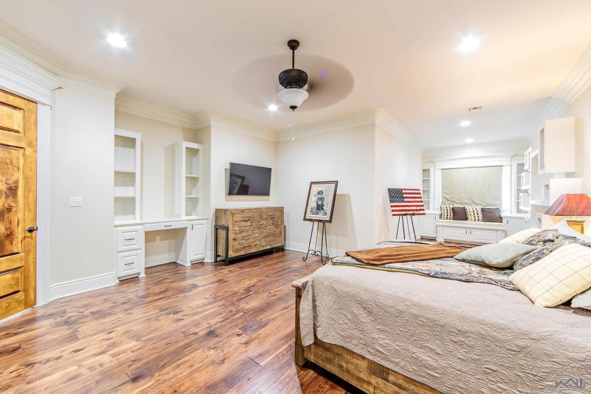 Bedroom with a large bed, TV and a wooden floor.