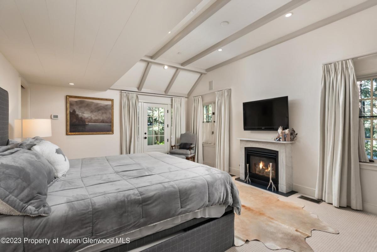 Bedroom with a large bed, custom lights, TV and a fireplace.