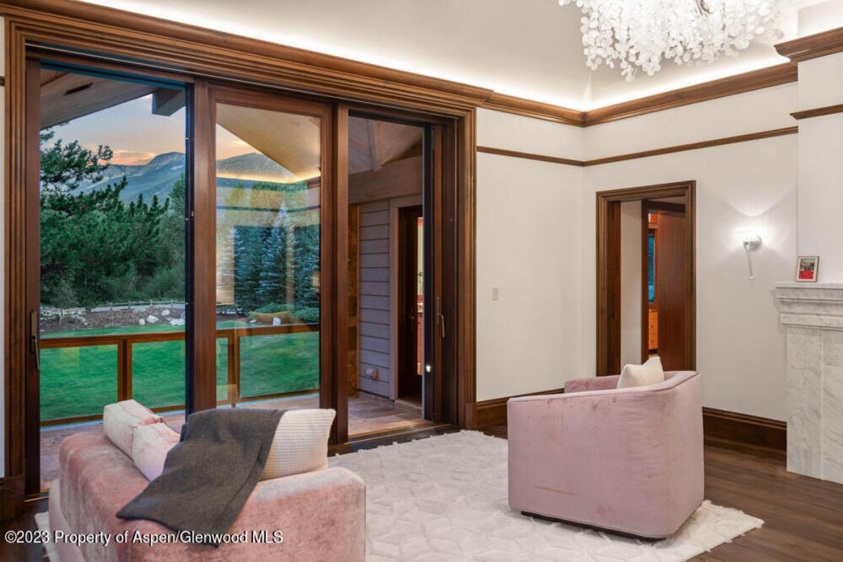 Bedroom with a sitting area, chandelier, glass doors and a wooden floor.