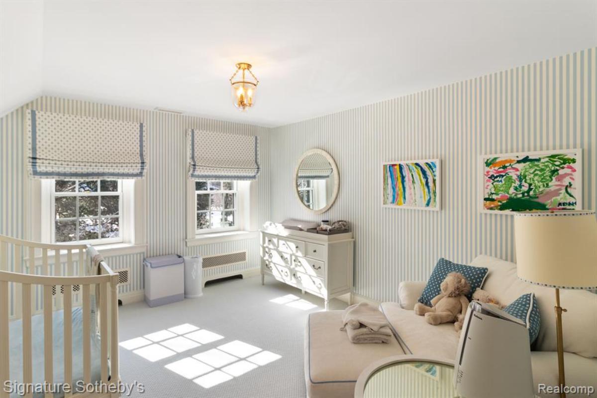 Baby's room with a crib, couch, glass windows and a carpet flooring.