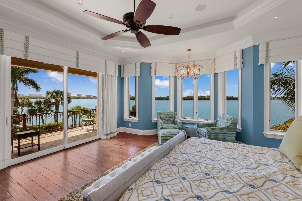Bedroom with a large bed, ceiling fan, and a wooden floor.