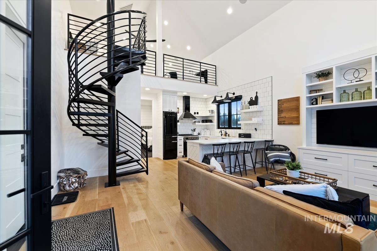 Living room with a couch, TV, spiral staircase and custom lights.