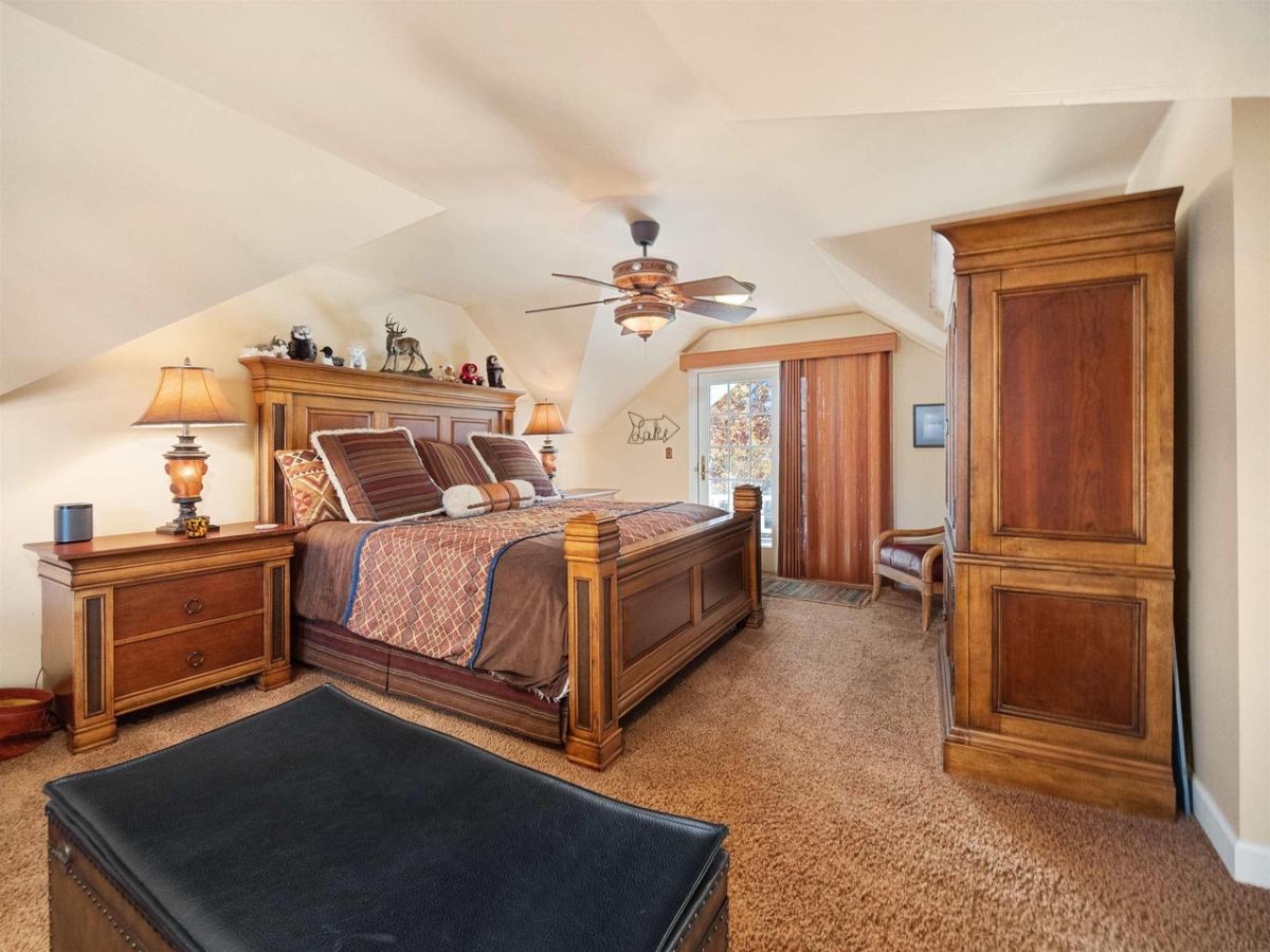 Bedroom with a large bed,  glass doors and carpet flooring.