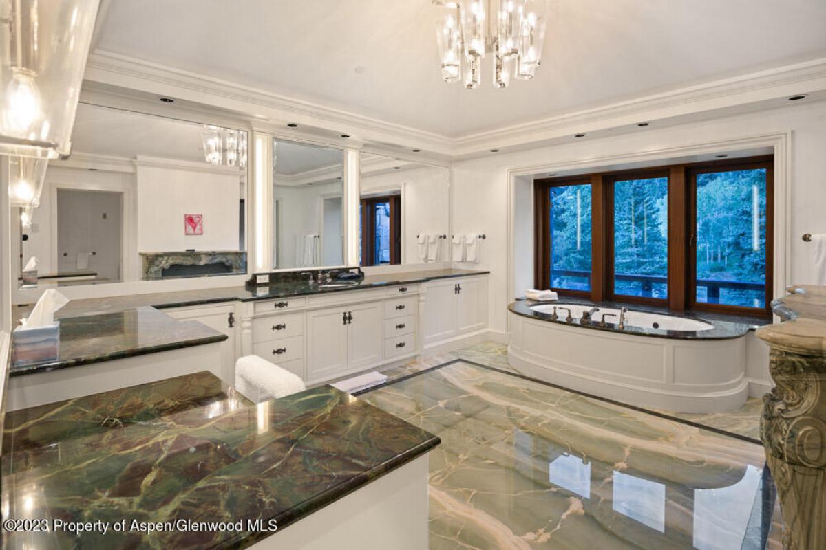 Bathroom with a sink, mirror, soaking tub and glass windows.