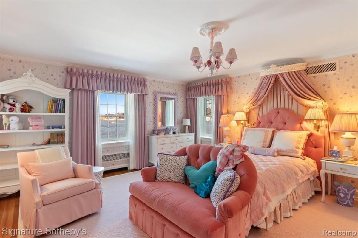 Bedroom with a large bed, chair, couch, large rug and glass windows.