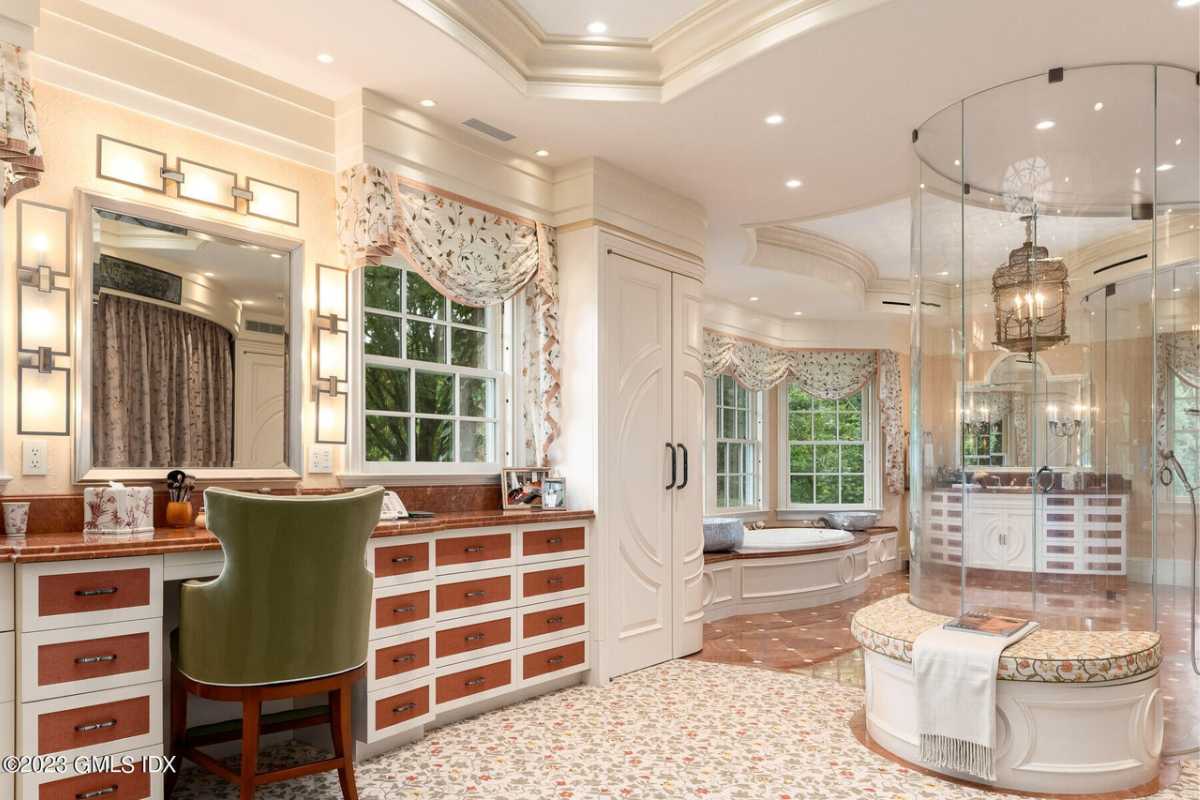 A bathroom with a bathtub, glass shower room, windows, cabinets, and a powder area.