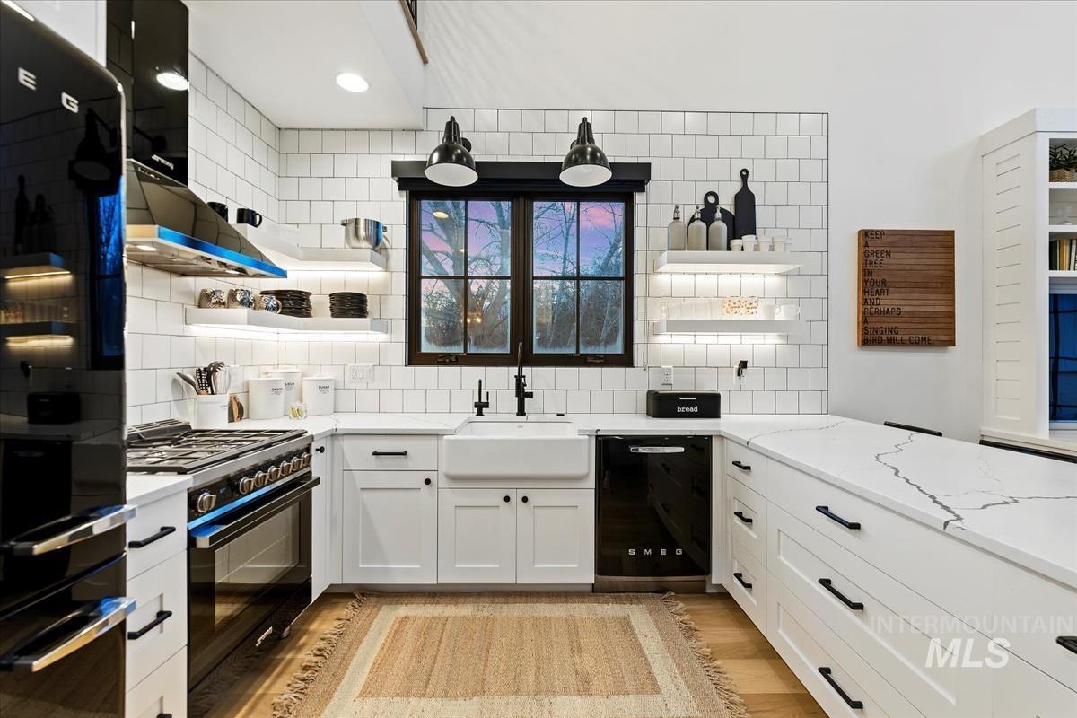 Kitchen with a stove, sink, glass windows and a wooden floor.