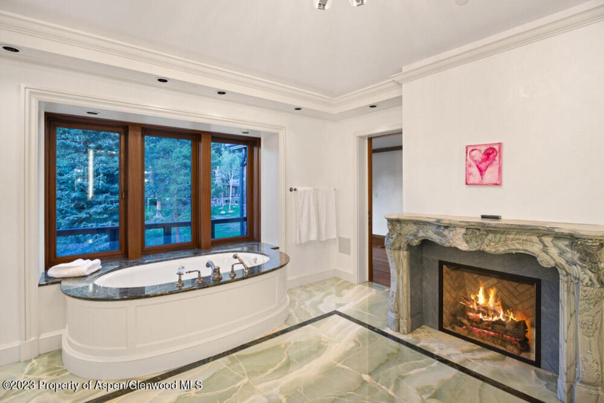 Bathroom with a fireplace, soaking tub and glass doors.