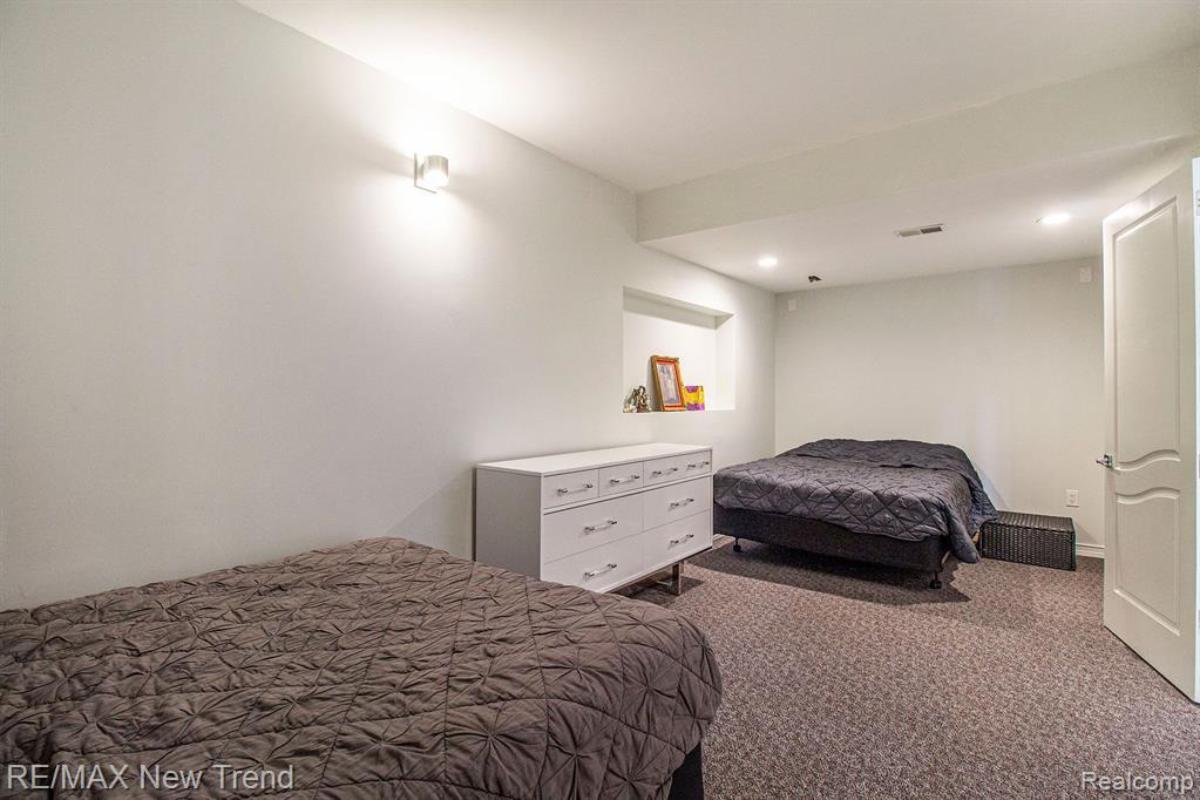 Bedroom with two beds, custom lights and carpet flooring.