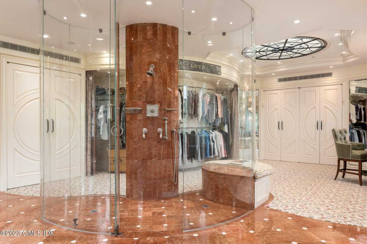 A bathroom featuring a glass shower room, closet, and skylight ceiling.