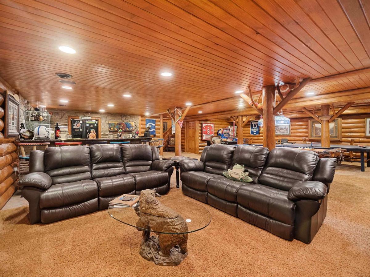 Entertainment room with couches, custom lights and wooden ceiling.