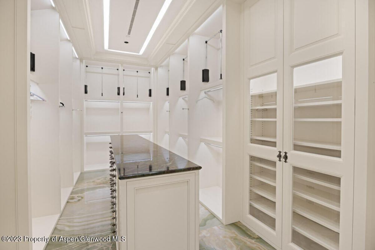 Walk-in closet with white cabinets and black counter tops.