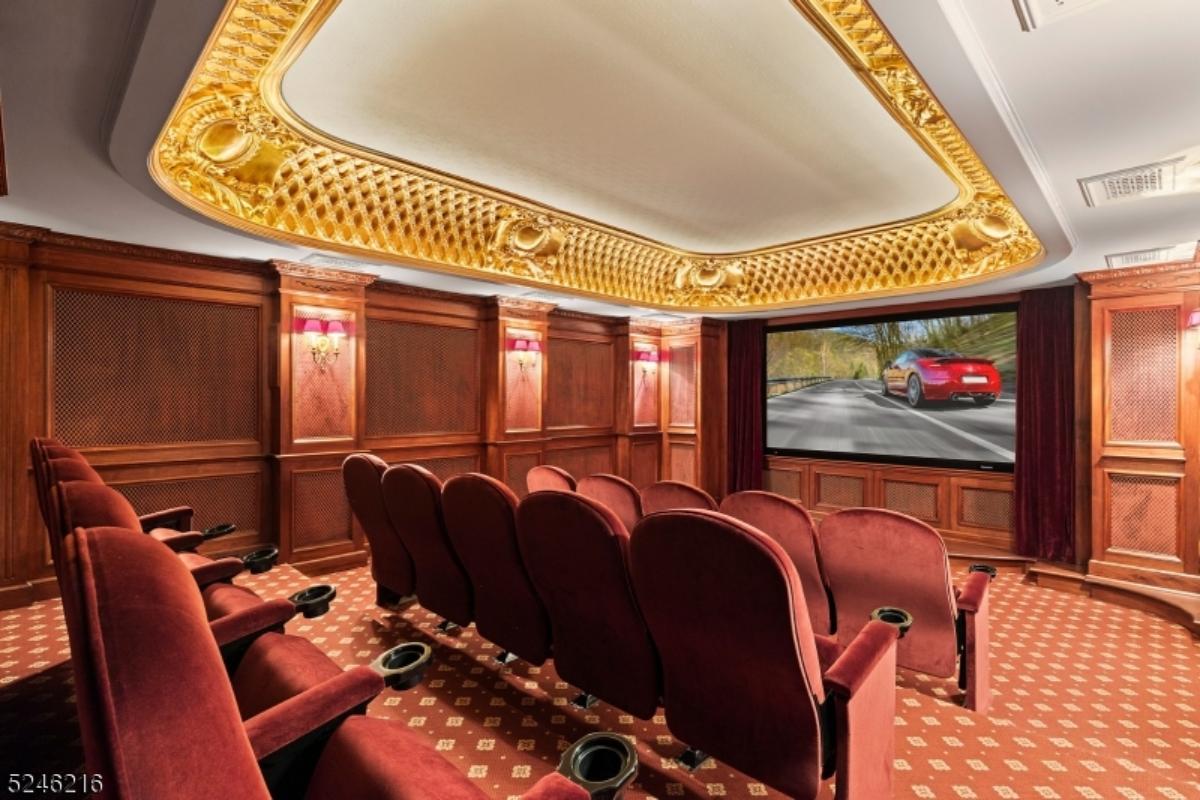 Home theater with a large screen, chairs and a carpet flooring.