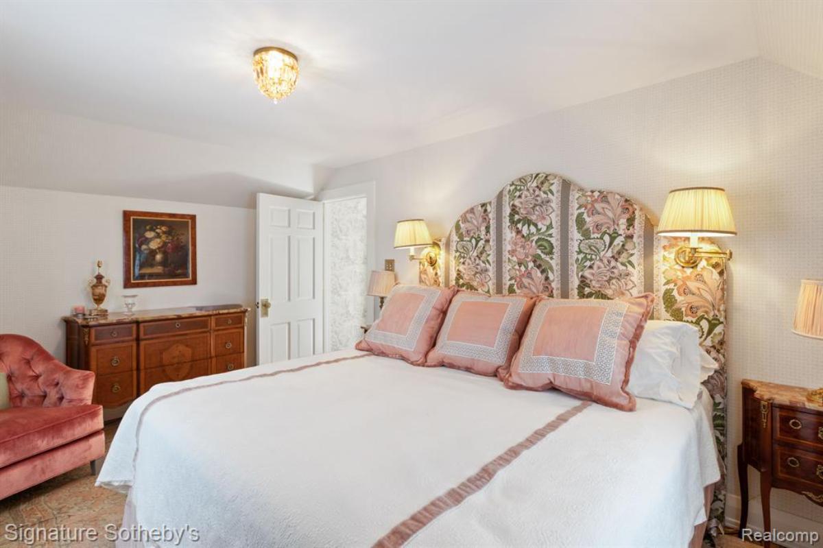 Bedroom with a large bed, couch, large rug and a wooden door.