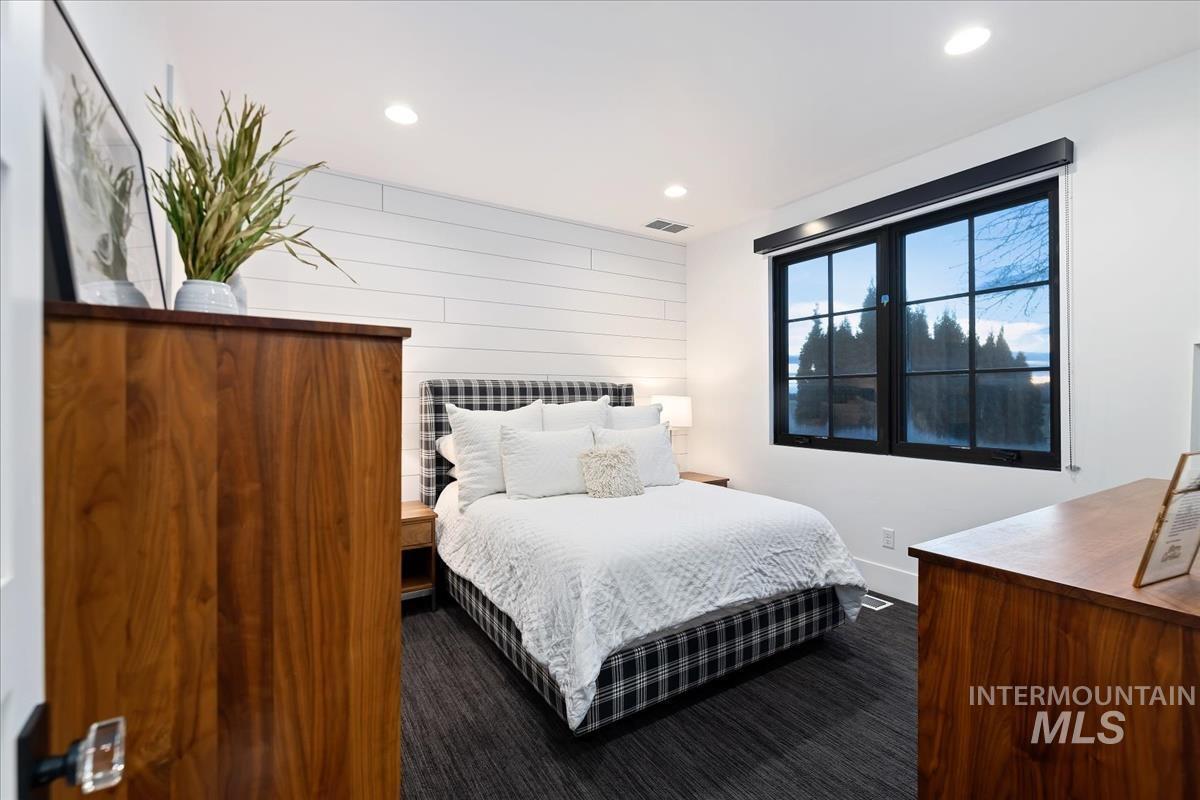 Bedroom with a large bed, glass windows and a carpet flooring.