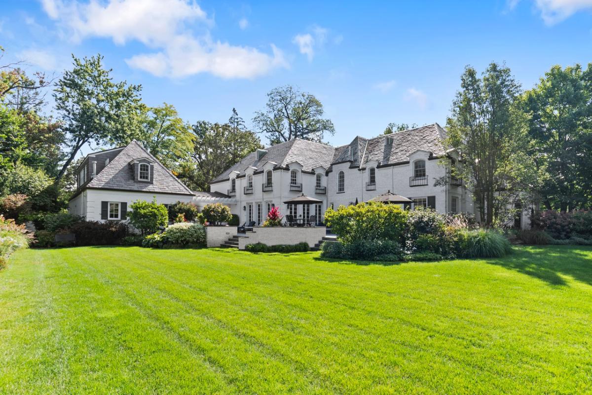 Exterior view of the mansion with trees in the background and a large green lawn.
