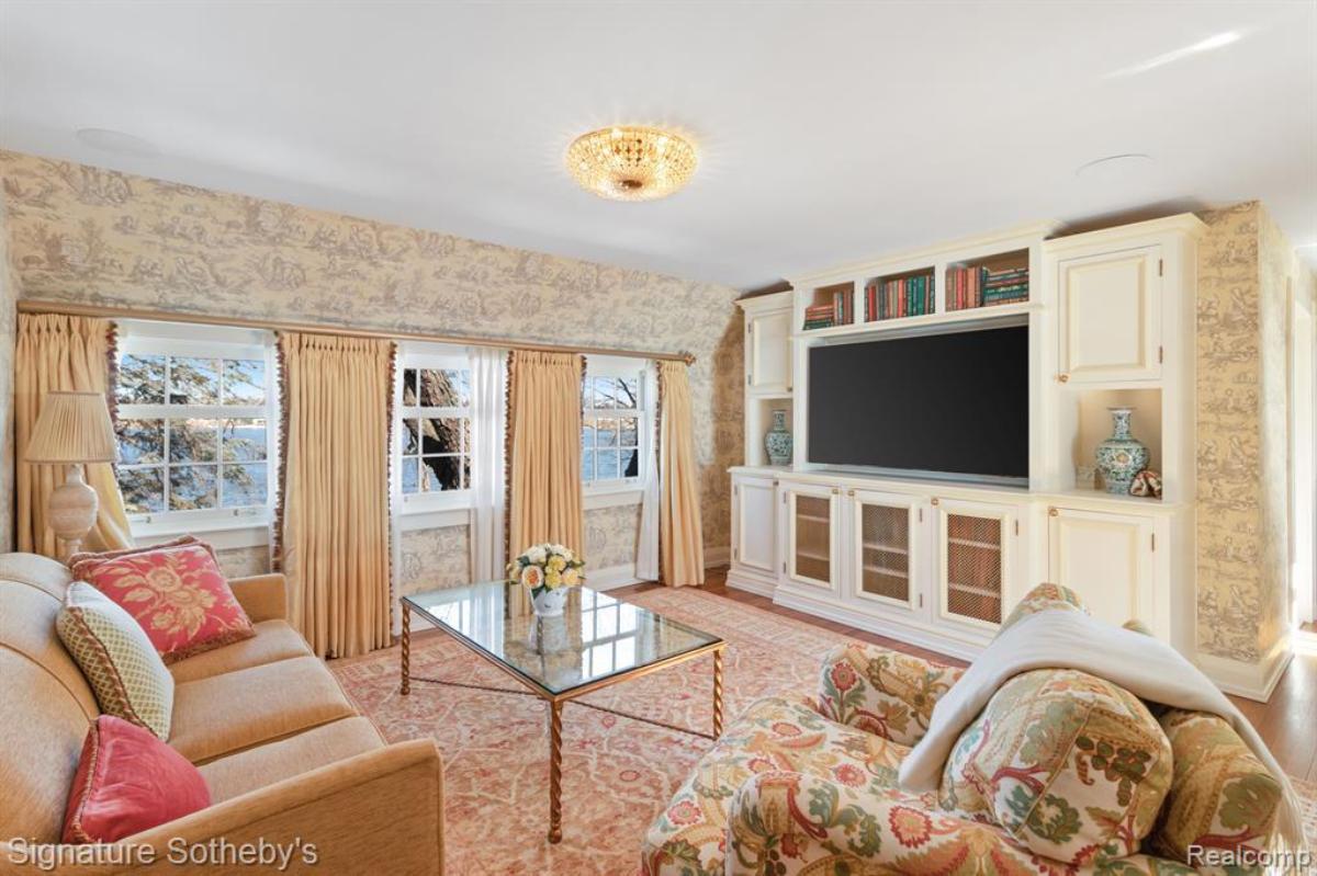 Living room with a couch, TV, glass windows and a large rug.
